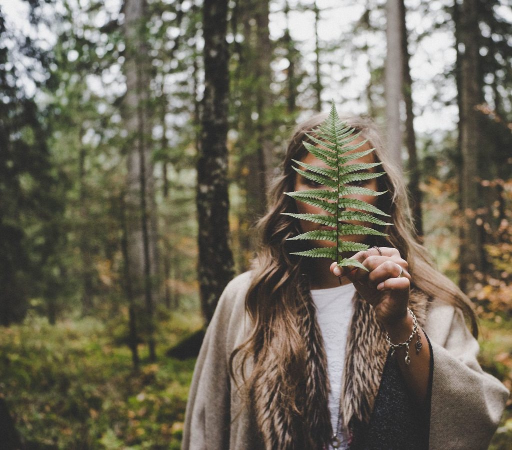 a woman looking at a leaf in the forest