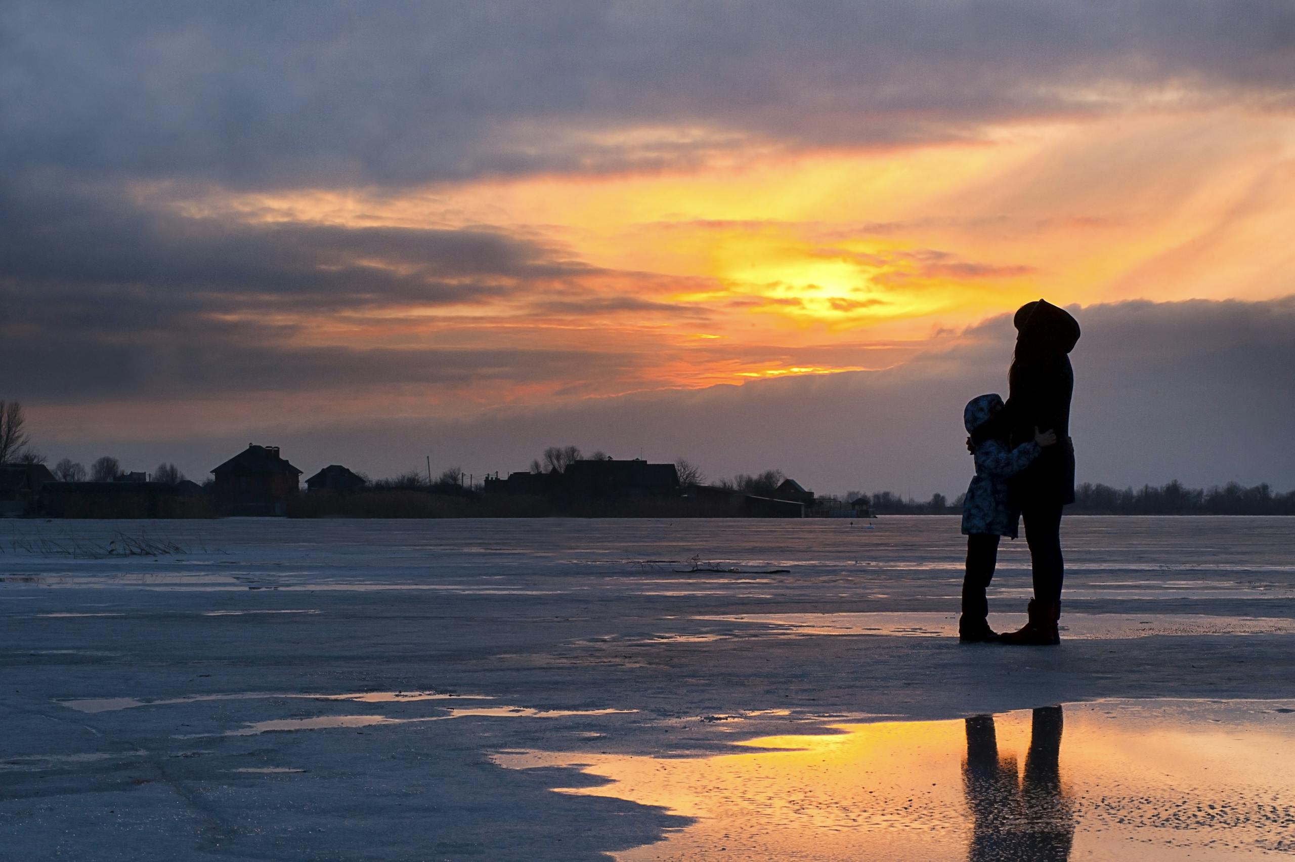 A serene sunset scene of a family silhouette on a frozen lake in Kherson, Ukraine.